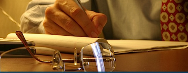 man at his desk writing on a peice of paper